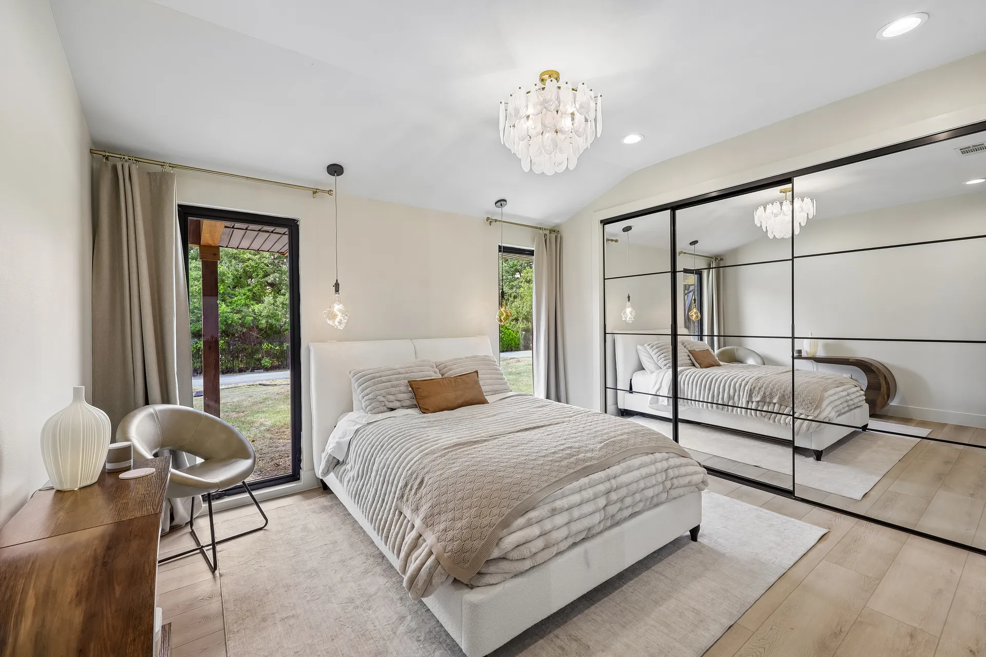 Wild Oak bedroom with cream upholstery, black framed mirrors, and a garden view
